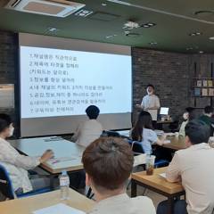 스크린 앞에서 발표하며 진행하는 소규모 강의 장면