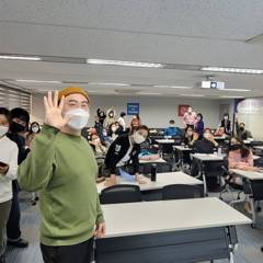 강의실에서 수강생들 앞에 손을 들며 인사하는 조피스