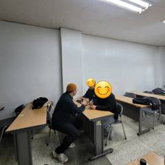 강의실에서 수강생과 일대일로 실습을 지도하는 장면